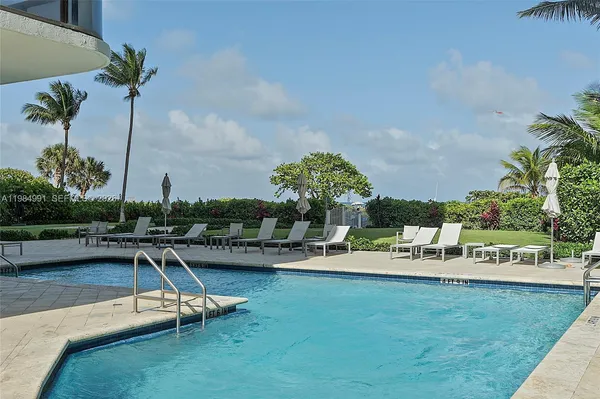 a view of a swimming pool with a bench and trees in the background