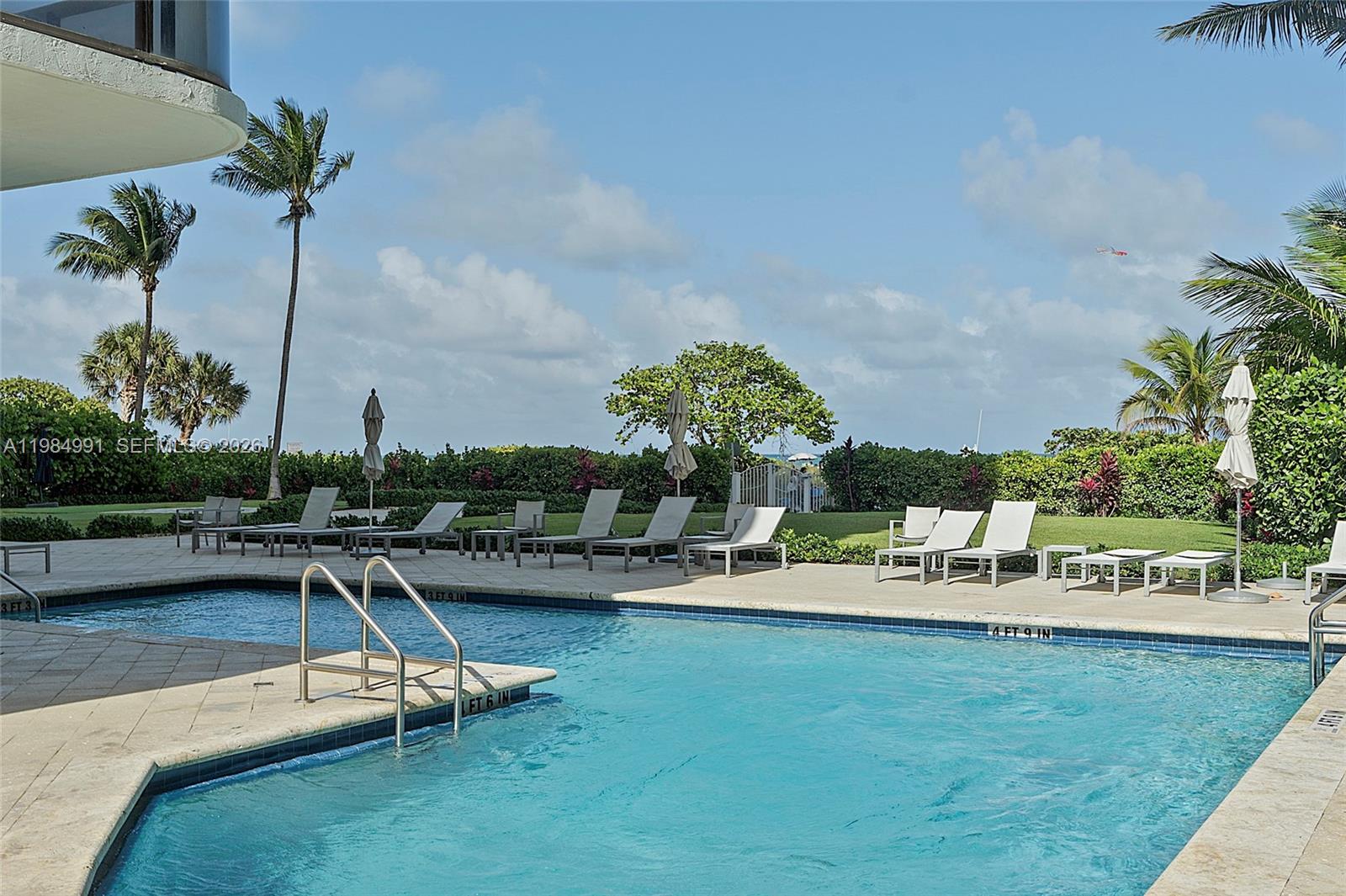 9455 Collins Avenue, Unit 409 Surfside, FL 33154 - Photo 8 of 46 a view of a swimming pool with a bench and trees in the background
