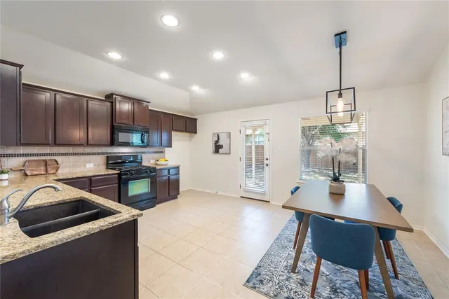 a kitchen with stainless steel appliances granite countertop a stove refrigerator a sink dishwasher and white cabinets with wooden floor