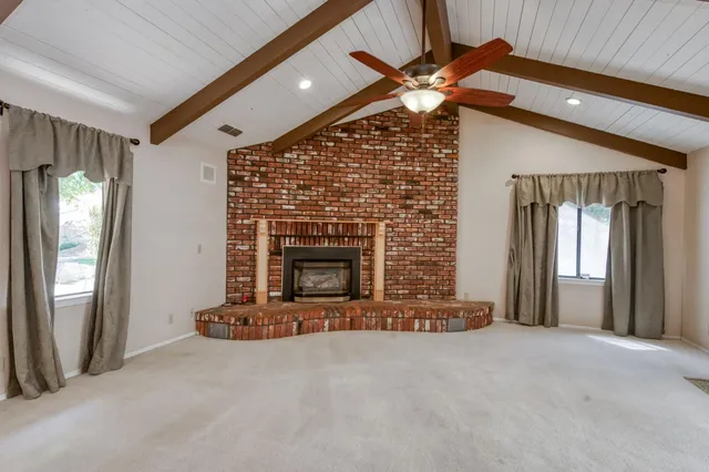 an empty room with chandelier fan and windows