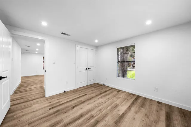 a view of an empty room with wooden floor and a window