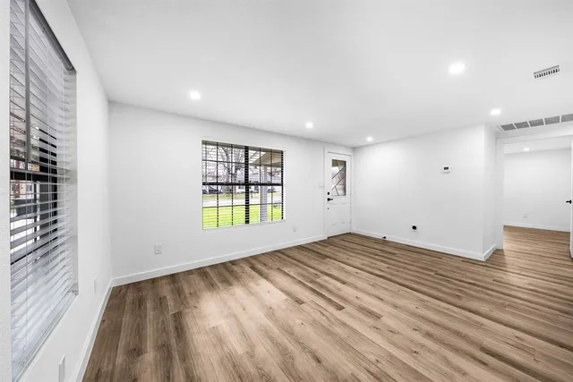 a view of an empty room with a window and wooden floor