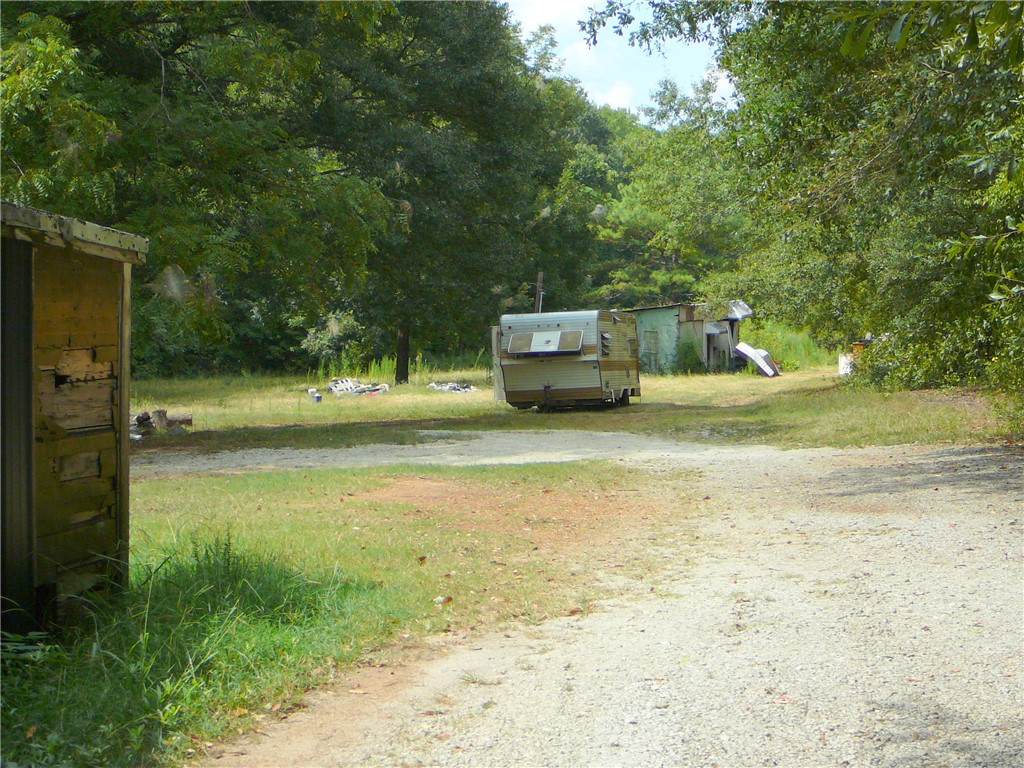 3208 Standridge Road Anderson, SC 29625 - Photo 1 of 1 Mature trees surround a gravel driveway leading into a private, wooded clearing.
