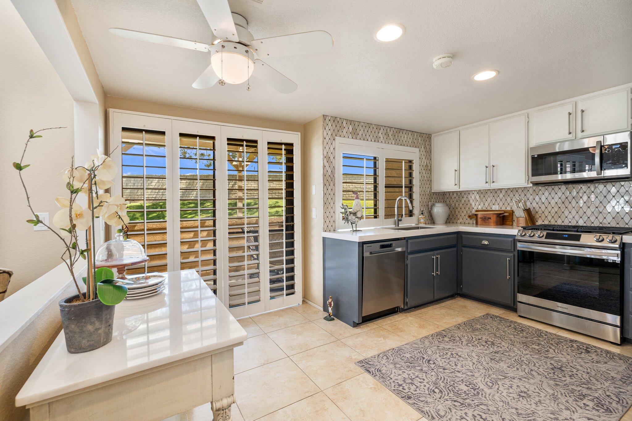 73750 Calle Bisque Palm Desert, CA 92260 - Photo 11 of 40 a kitchen with stainless steel appliances granite countertop a stove a sink a microwave a dining table and chairs with wooden floor