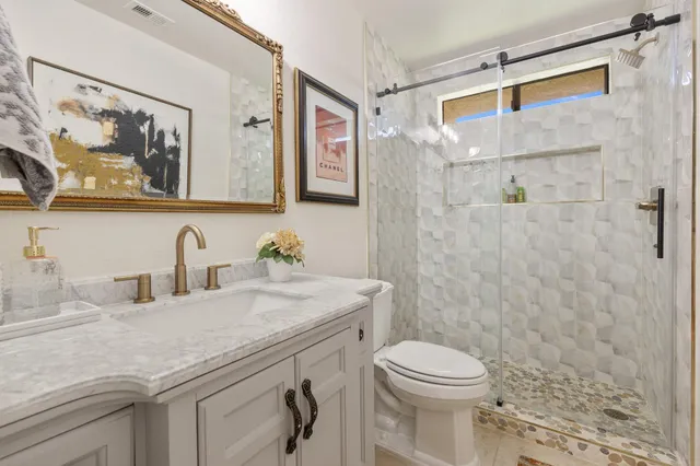 a bathroom with a granite countertop sink toilet and shower