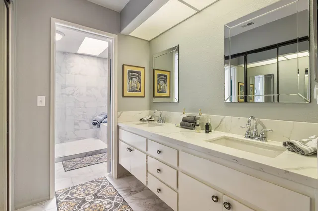 a bathroom with double vanity sinks a large mirror and a bathtub