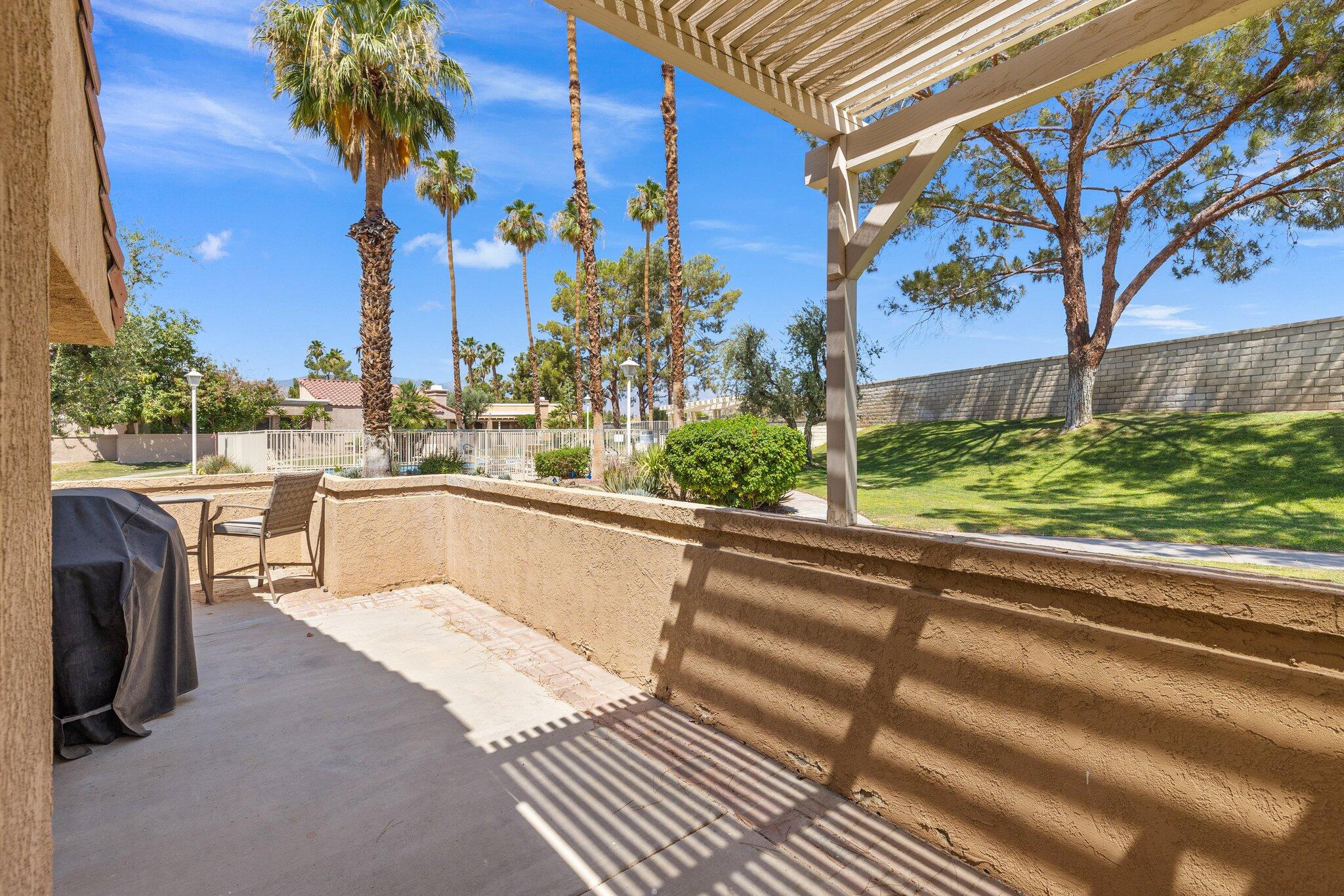 73750 Calle Bisque Palm Desert, CA 92260 - Photo 28 of 40 a view of a swimming pool with a lawn chairs under an umbrella