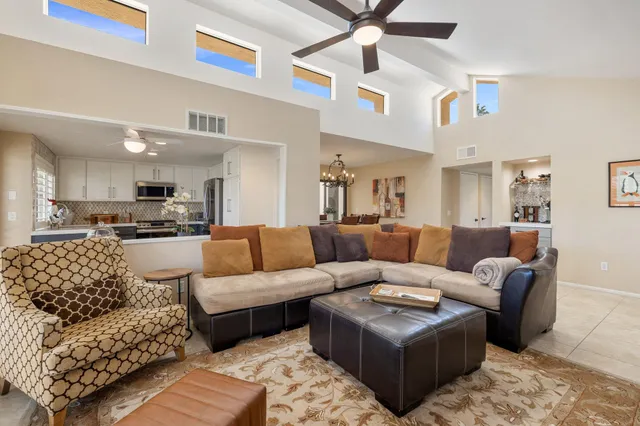a living room with furniture kitchen view and a chandelier