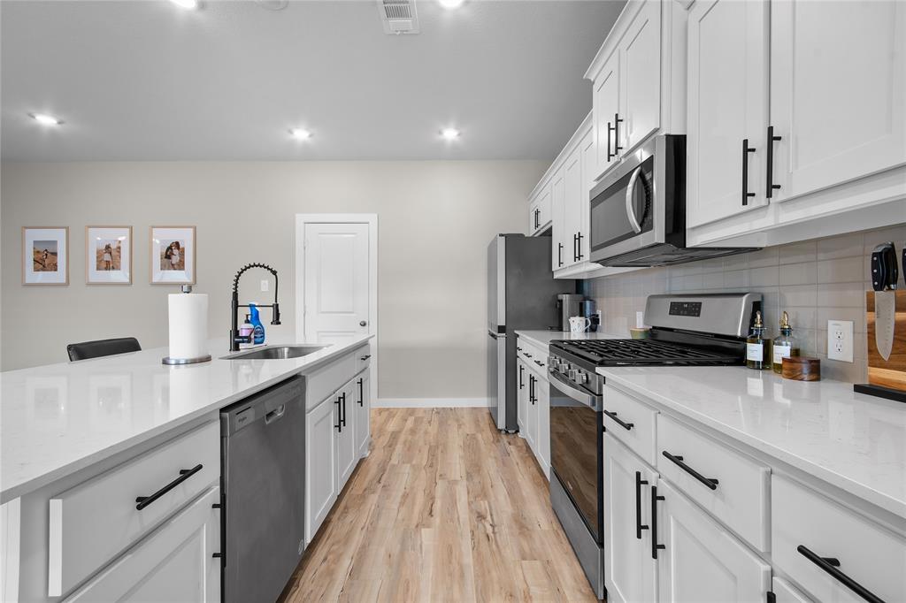 797 Vineyard Way Forney, TX 75126 - Photo 5 of 24 a kitchen with stainless steel appliances a sink stove and cabinets