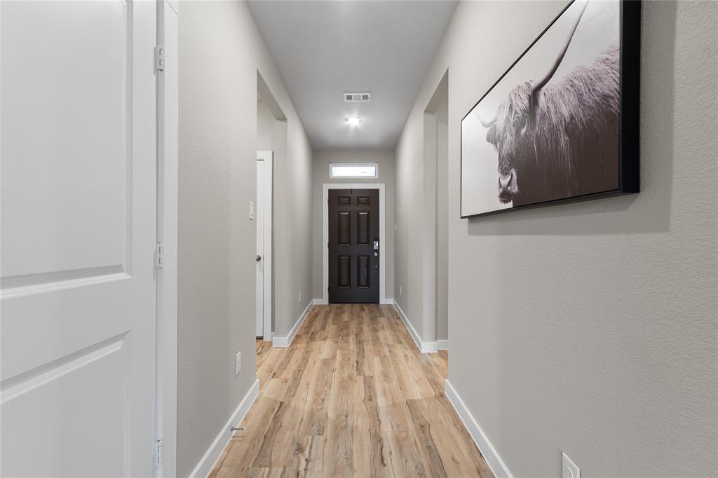 797 Vineyard Way Forney, TX 75126 - Photo 7 of 24 a view of a hallway with wooden floor and cabinet