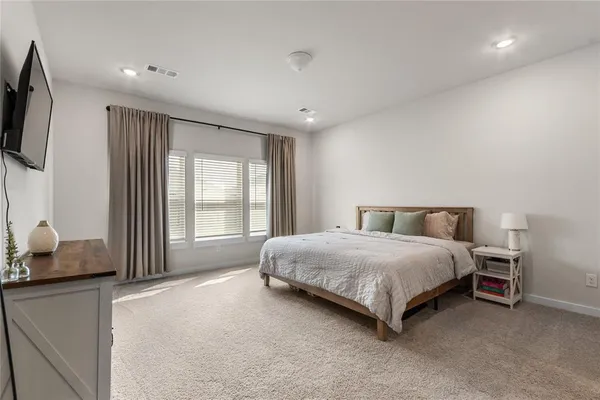 a spacious bedroom with a bed and flat screen tv