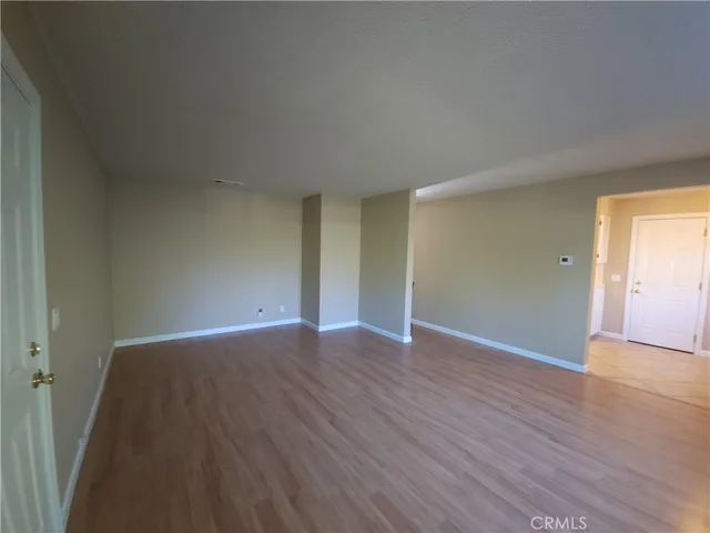 a view of an empty room with wooden floor and closet