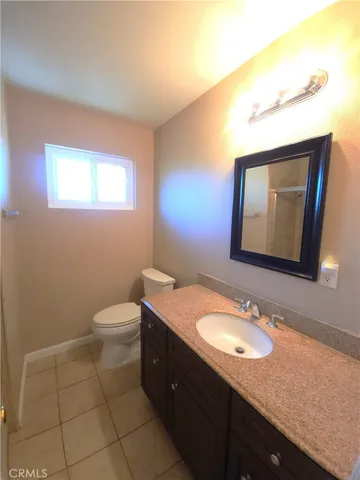 a bathroom with a granite countertop toilet sink and mirror