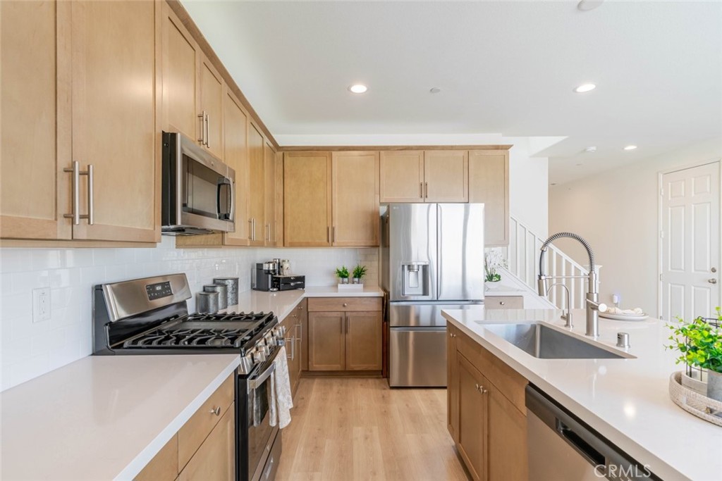 2133 East Kettering Street Lancaster, CA 93535 - Photo 5 of 32 a kitchen with stainless steel appliances a sink stove and cabinets