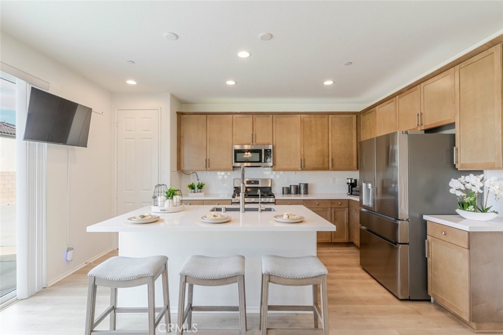 2133 East Kettering Street Lancaster, CA 93535 - Photo 7 of 32 a kitchen with refrigerator a microwave and chairs