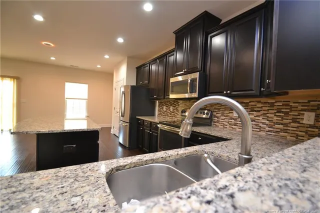 a kitchen with kitchen island granite countertop a sink and wooden cabinets