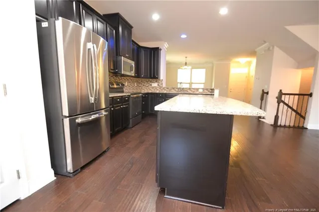 a kitchen with stainless steel appliances granite countertop a refrigerator a stove and a sink