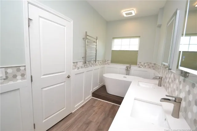 a spacious bathroom with a double vanity sink a mirror and a bathtub