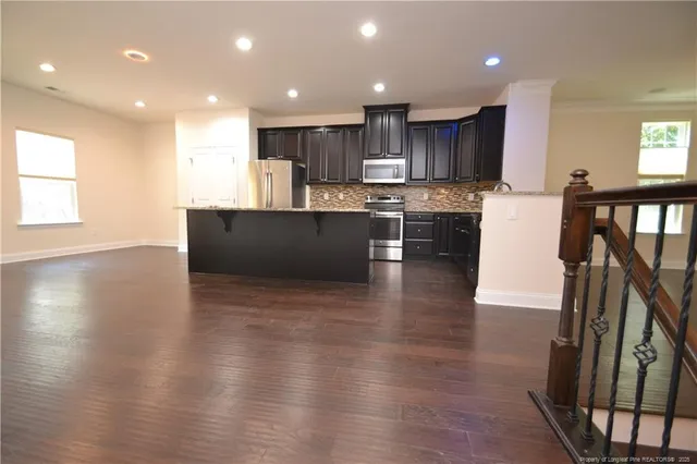 an open kitchen with wooden floor and stainless steel appliances