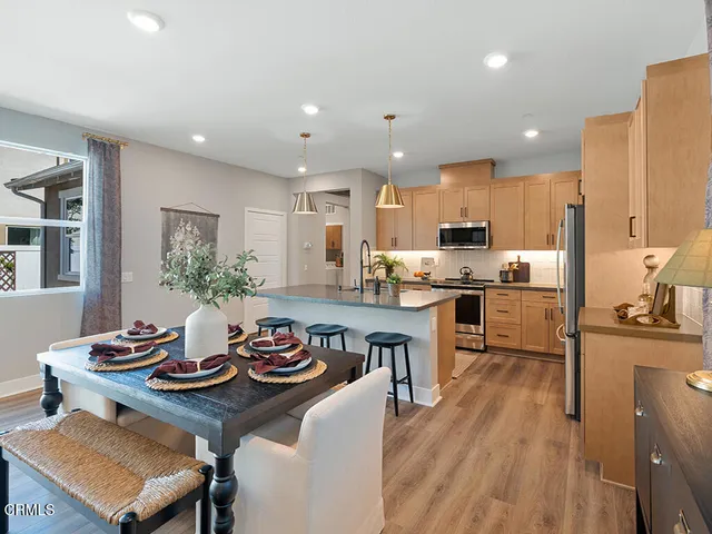 a kitchen with kitchen island granite countertop a sink a stove a refrigerator cabinets and dining table