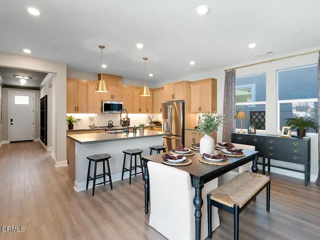a kitchen with a dining table chairs refrigerator and wooden floor