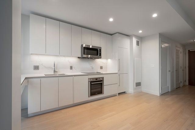 a kitchen with stainless steel appliances granite countertop a sink and white cabinets