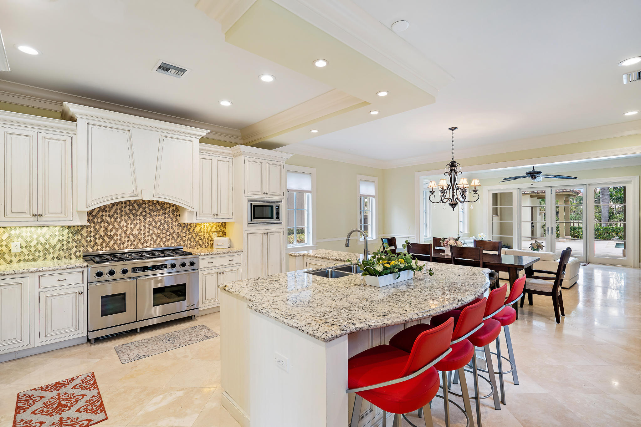 426 Red Hawk Drive Jupiter, FL 33477 - Photo 5 of 40 a kitchen with kitchen island granite countertop a stove a sink a dining table and chairs