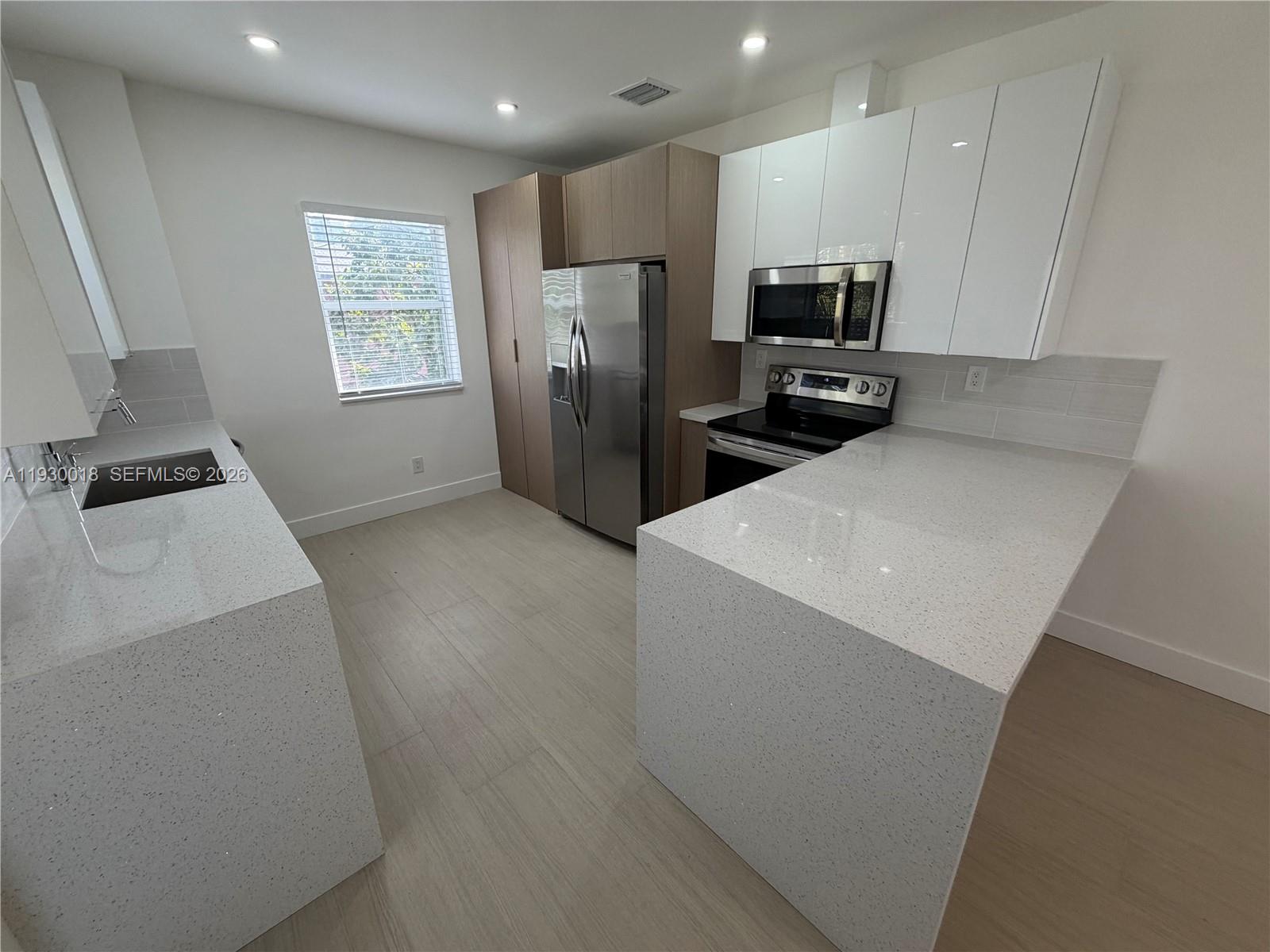 a kitchen with granite countertop a refrigerator and a stove top oven