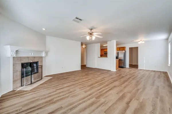 a view of an empty room with a fireplace and chandelier fan