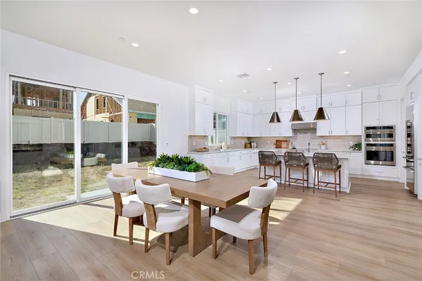 a kitchen with stainless steel appliances granite countertop a kitchen island a stove a refrigerator a sink a table and chairs