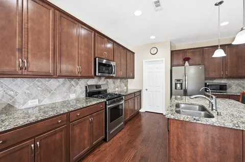 a kitchen with stainless steel appliances granite countertop a sink dishwasher stove and microwave with wooden cabinets
