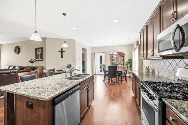 a very nice looking kitchen with granite countertop a stove a sink a dining table and chairs