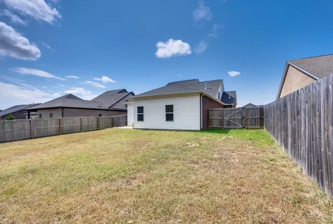 a view of a house with backyard and wooden fence