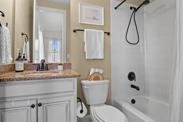 a bathroom with a granite countertop sink a toilet and a bathtub