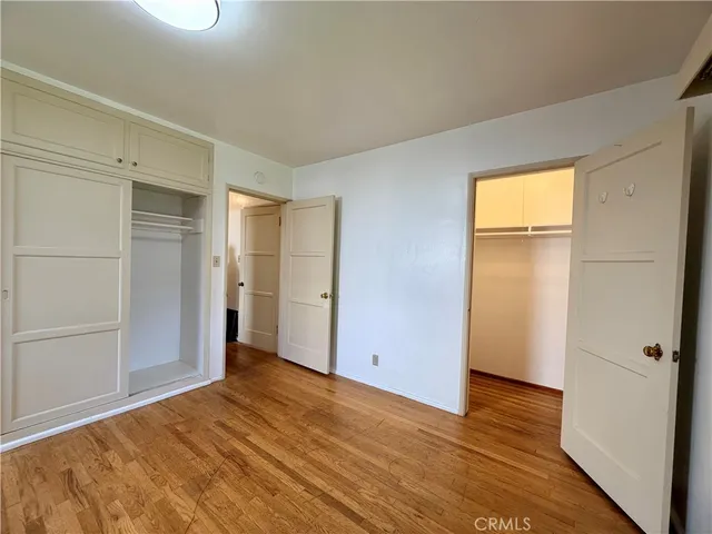 a view of an empty room with wooden floor and closet
