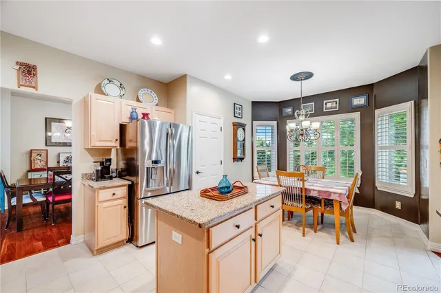 a very nice looking open dining room with kitchen island furniture a refrigerator a sink and a large window