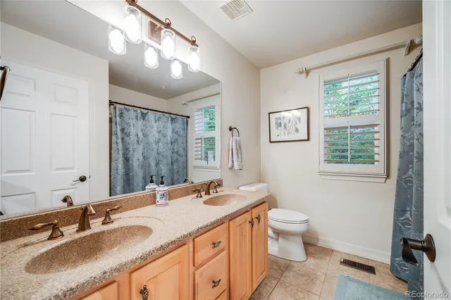 a bathroom with a granite countertop double vanity sink a mirror and a toilet
