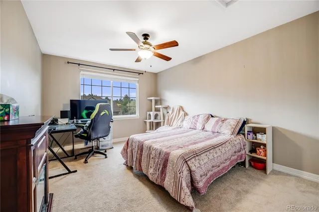 a bedroom with a bed a desk and chair with a bookshelf