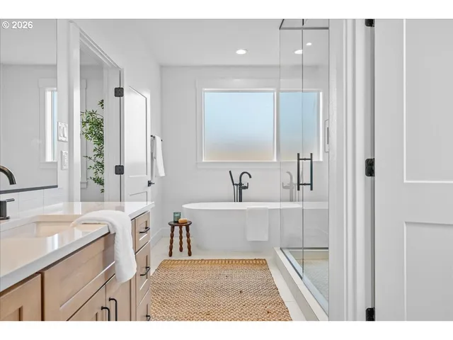 a bathroom with a sink a bathtub a mirror a vanity and a shower