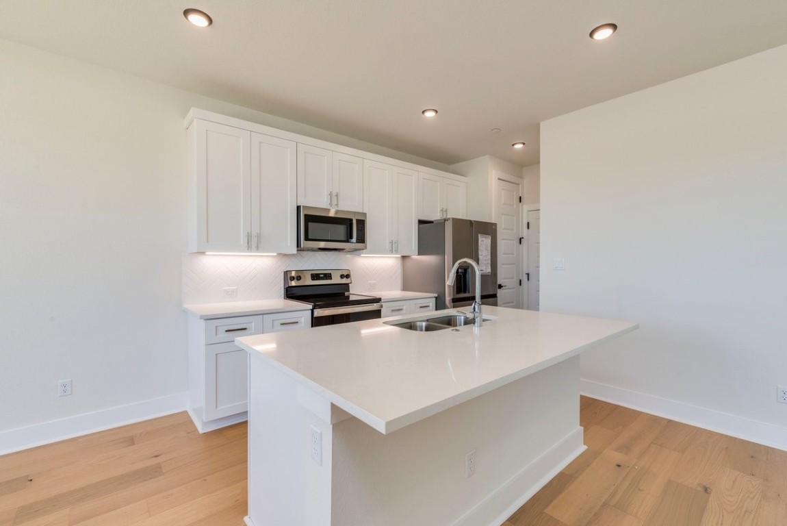2600 Gattis School Road, Unit 101 Round Rock, TX 78664 - Photo 5 of 23 a kitchen with appliances a sink cabinets and wooden floor