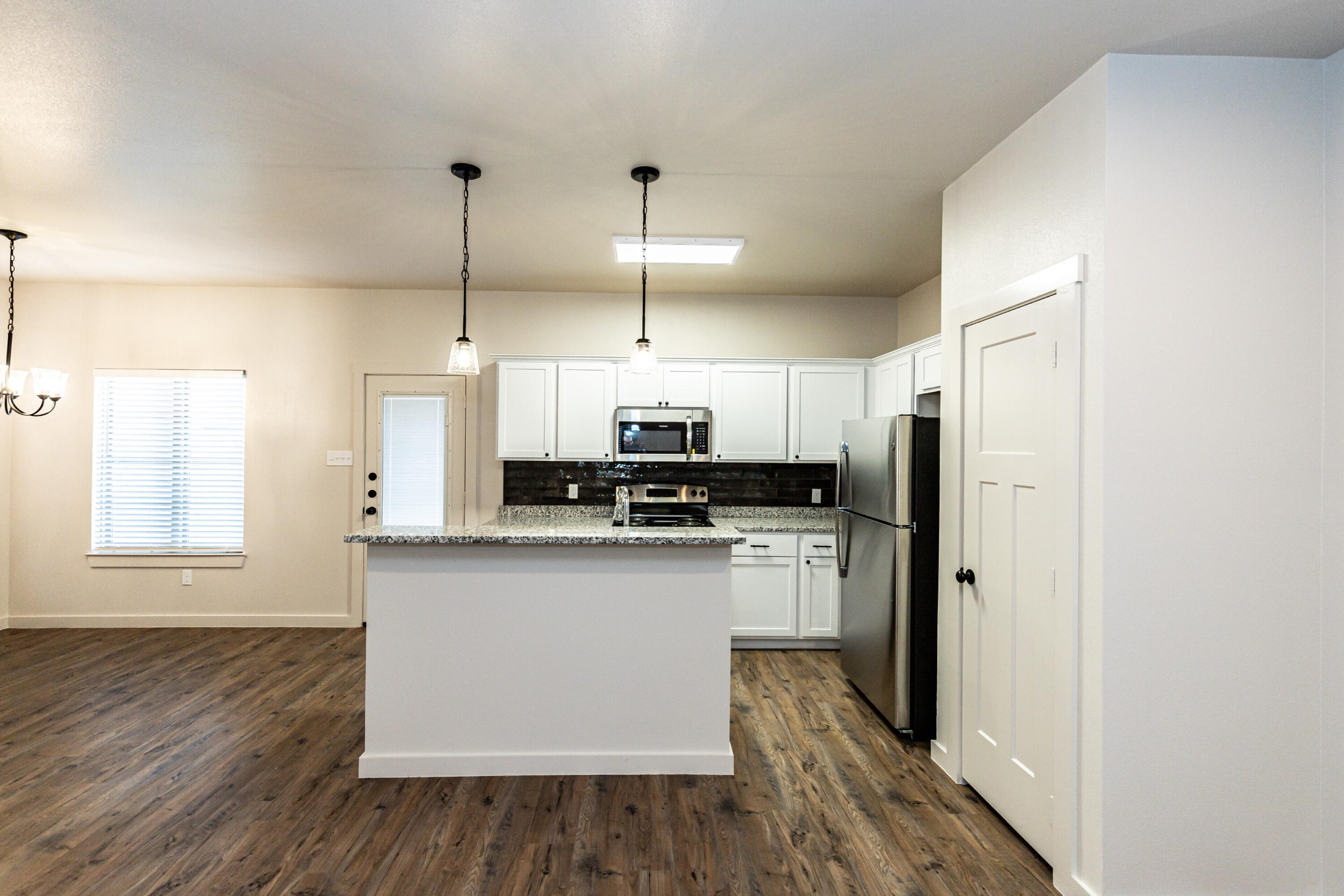 2526 138th Street Lubbock, TX 79423 - Photo 12 of 36 a kitchen with stainless steel appliances a refrigerator a sink dishwasher a stove and white cabinets with wooden floor
