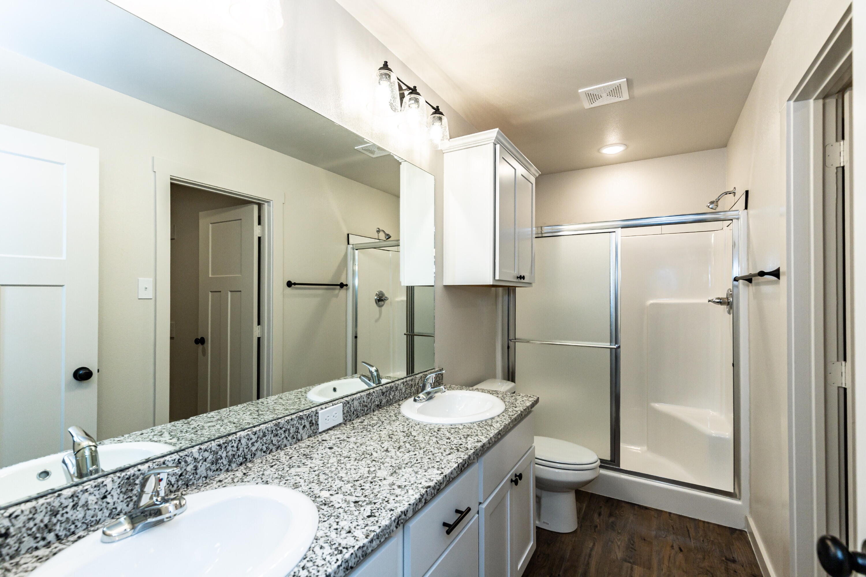 2526 138th Street Lubbock, TX 79423 - Photo 26 of 36 a bathroom with a granite countertop sink a toilet and shower