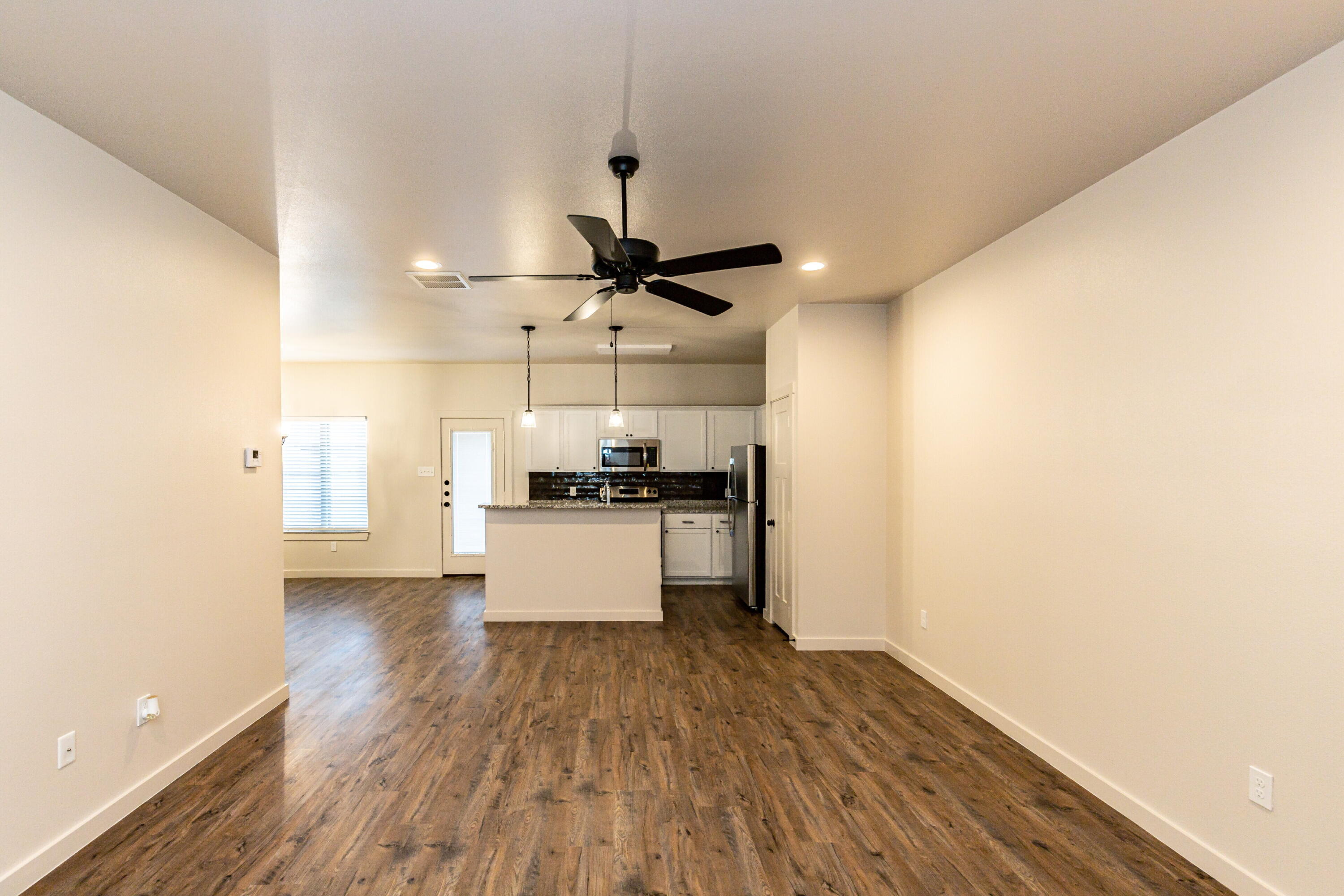 2526 138th Street Lubbock, TX 79423 - Photo 8 of 36 a view of kitchen and empty room with wooden floor