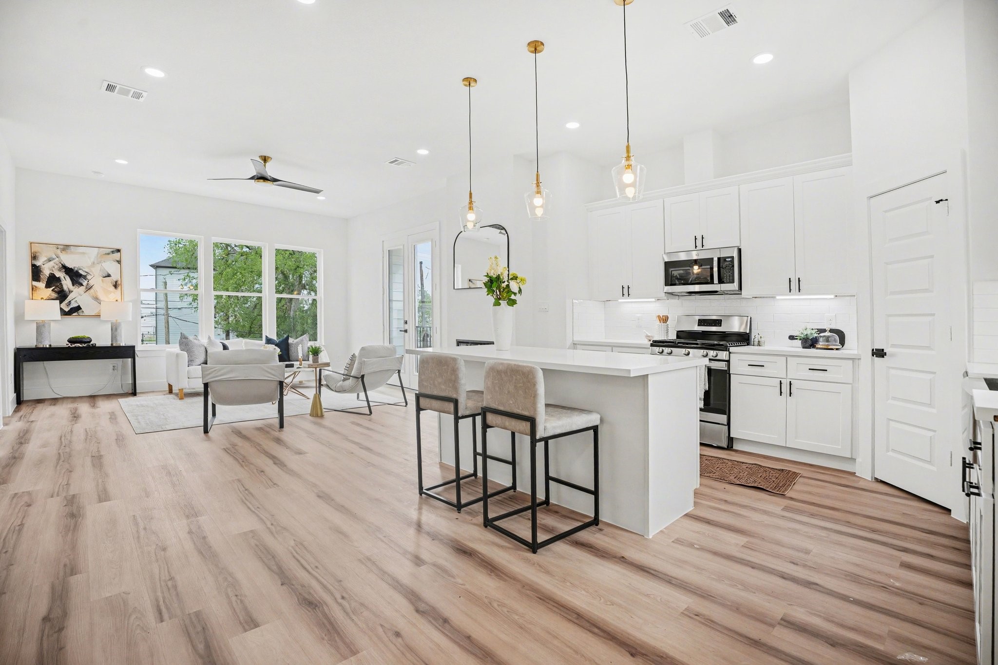 115 Milby Street Houston, TX 77003 - Photo 6 of 28 Bright, open-concept kitchen and living area with modern finishes. Features include sleek white cabinetry, stainless steel appliances, pendant lighting, and large windows offering natural light and views. Perfect for entertaining.