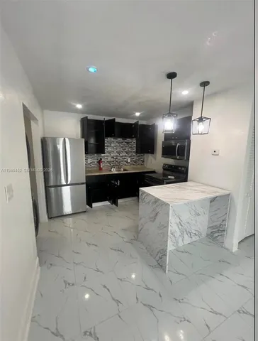 a view of a kitchen with refrigerator and chairs