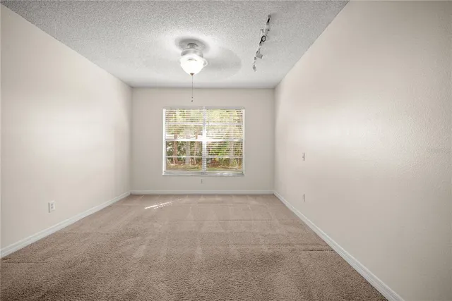an empty room with windows and chandelier fan