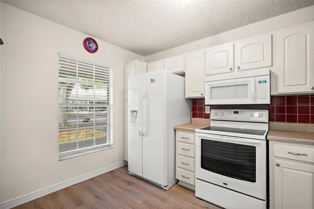 a kitchen with cabinets appliances and wooden floor