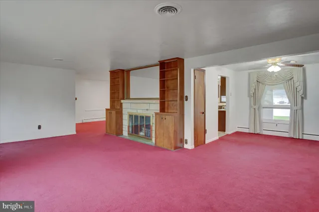 an empty room with chandelier fan and windows