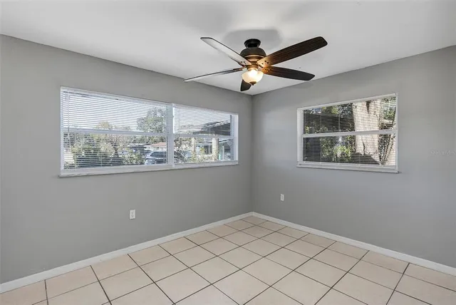 an empty room with a ceiling fan and window