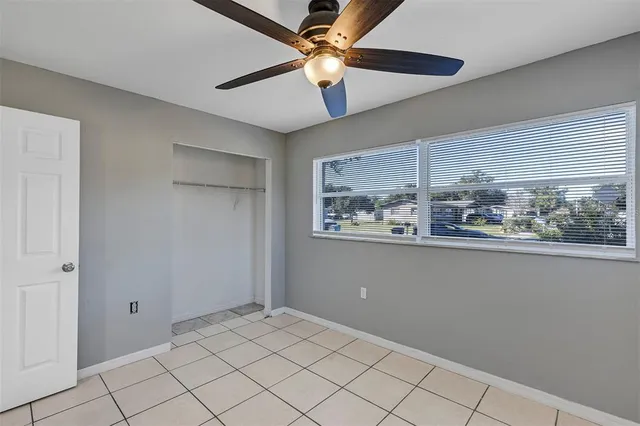 a view of an empty room with window and chandelier fan